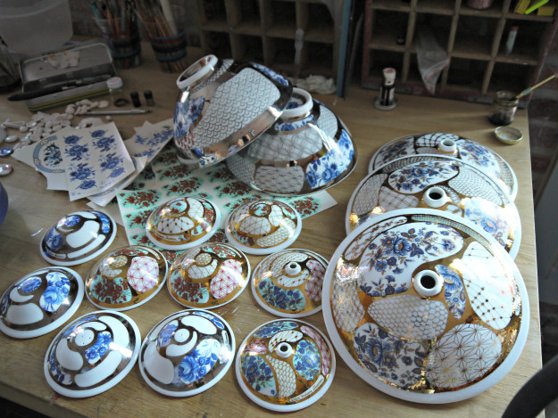 Working on some small and large budvases, salt & pepper shaker, applying decals and gold luster Working on some small and large budvases, salt & pepper shaker, applying decals and gold luster